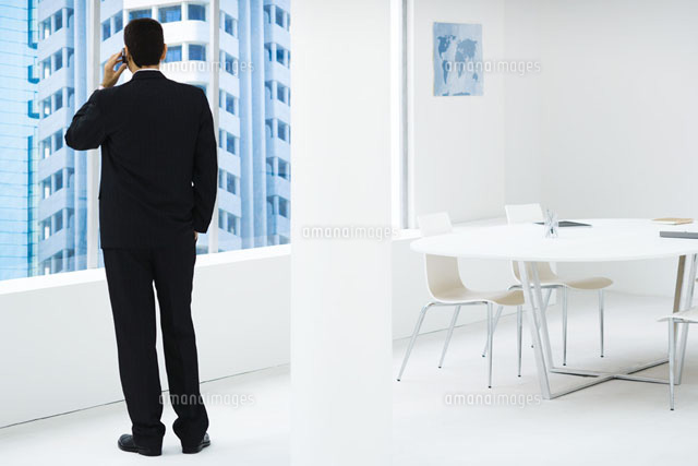 Businessman standing,looking out window,using cell phone
(c)Frederic Cirou/PhotoAlto