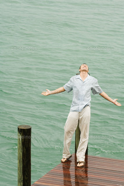 Man leaning back on pier in the rain,arms out
(c)Odilon Dimier/PhotoAlto