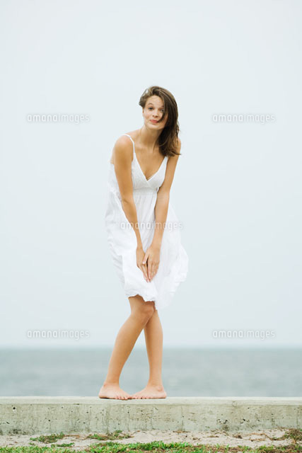 Girl in front of the sea,bending over to hold skirt
(c)Odilon Dimier/PhotoAlto