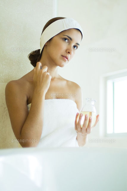 Young woman wrapped in towel applying perfume to neck
(c)Odilon Dimier/PhotoAlto