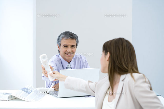 Businessman handing female associate telephone
(c)Sigrid Olsson/PhotoAlto
