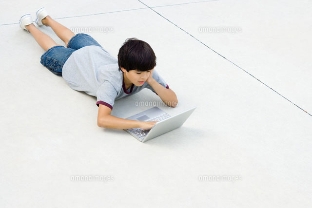 Boy lying on stomach on the ground,using laptop computer
(c)Frederic Cirou/PhotoAlto