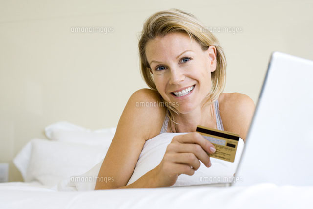 Woman lying in bed with laptop,holding credit card
(c)Frederic Cirou/PhotoAlto