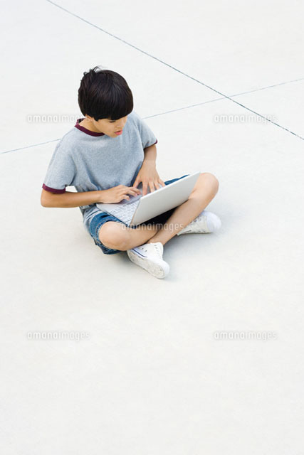 Boy sitting cross-legged on the ground,using laptop
(c)Frederic Cirou/PhotoAlto