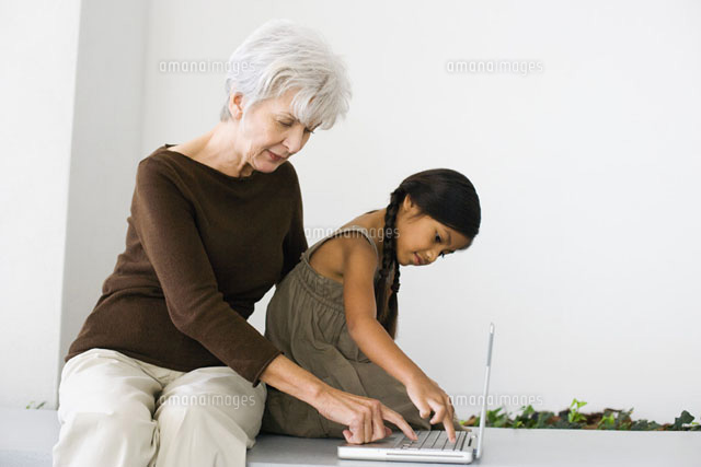 Woman sitting behind granddaughter,typing on laptop
(c)Frederic Cirou/PhotoAlto