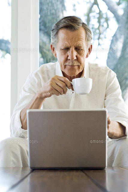 Man holding coffee cup,looking down at laptop
(c)Frederic Cirou/PhotoAlto