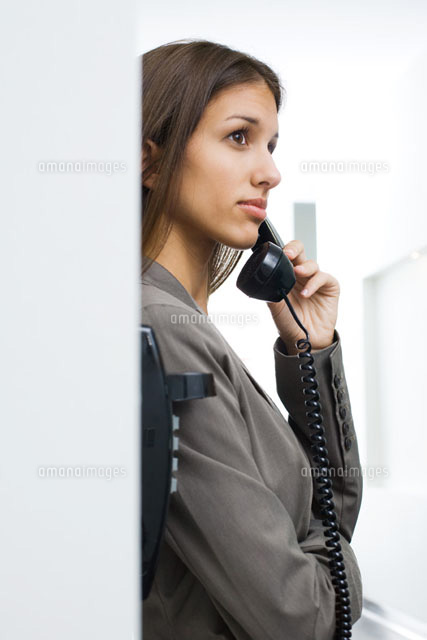 Girl leaning against wall,using landline phone
(c)Frederic Cirou/PhotoAlto