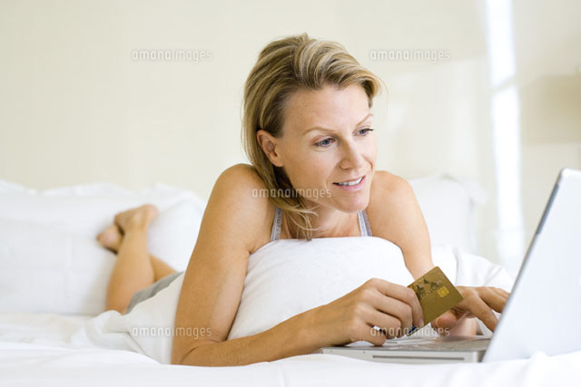 Woman lying on stomach in bed,using laptop and credit card
(c)Frederic Cirou/PhotoAlto
