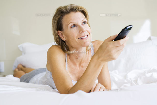 Woman lying on stomach in bed,holding remote control
(c)Frederic Cirou/PhotoAlto