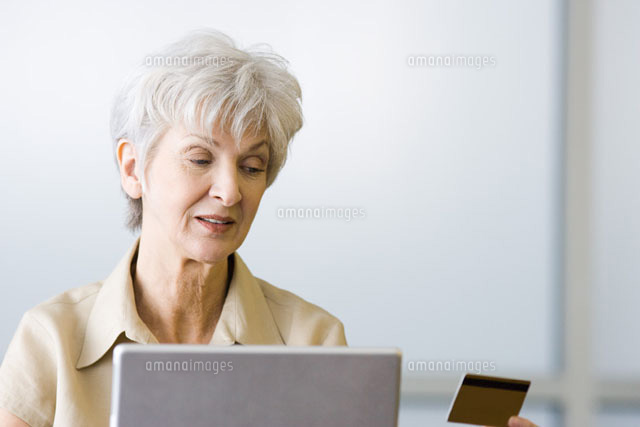Senior woman looking at credit card,sitting behind laptop
(c)Frederic Cirou/PhotoAlto