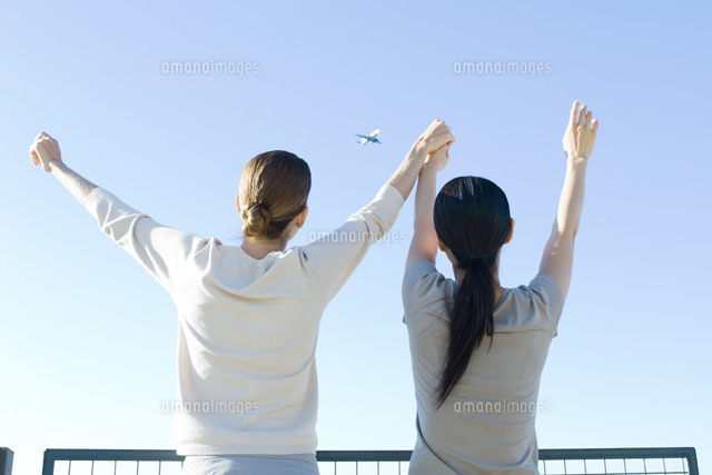 Women looking at airplane in sky,holding hands
(c)Michele Constantini/PhotoAlto