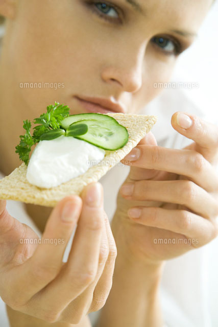 Woman holding up cracker with cucumbers and cheese spread
(c)Rafal Strzechowski/PhotoAlto