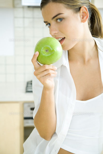 Young woman pretending to bite apple,smiling at camera
(c)Rafal Strzechowski/PhotoAlto
