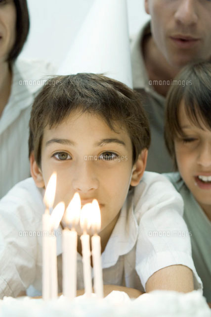 Boy behind birthday cake with lit candle,wearing party hat
(c)Odilon Dimier/PhotoAlto