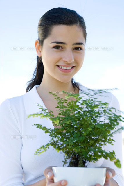 Young woman holding potted plant,smiling at camera
(c)Sigrid Olsson/PhotoAlto