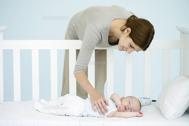 Mother leaning over side of crib to check sleeping infant
(c)Ale Ventura/PhotoAlto