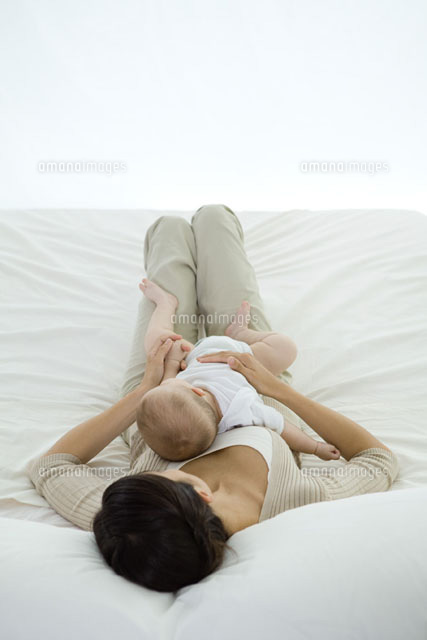 Woman lying on bed,holding infant on her stomach
(c)Ale Ventura/PhotoAlto
