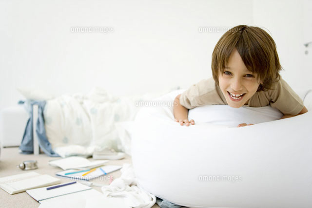 Boy lying on stomach in messy room,smiling at camera
(c)Sigrid Olsson/PhotoAlto