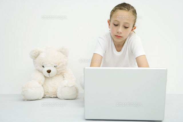 Girl sitting beside teddy bear,using laptop computer
(c)Sigrid Olsson/PhotoAlto