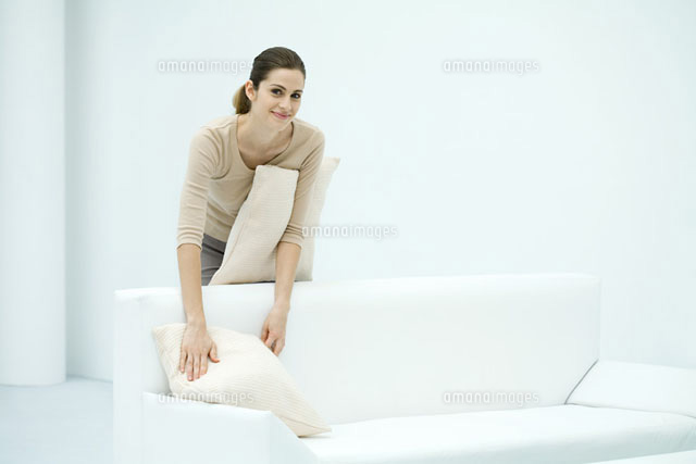 Woman arranging pillows on sofa,smiling at camera
(c)Ale Ventura/PhotoAlto