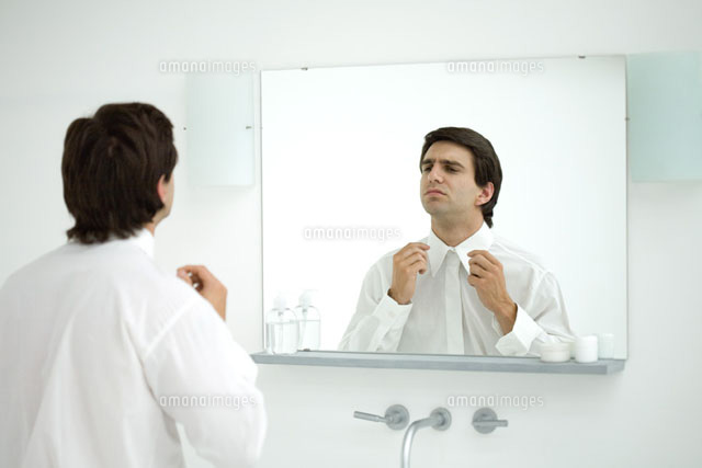 Man wearing button down shirt,adjusting collar in mirror
(c)Ale Ventura/PhotoAlto