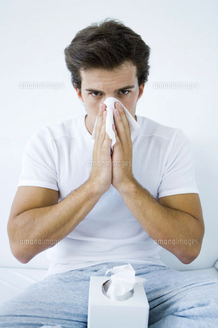 Man blowing his nose with a tissue,looking at camera
(c)Alix Minde/PhotoAlto
