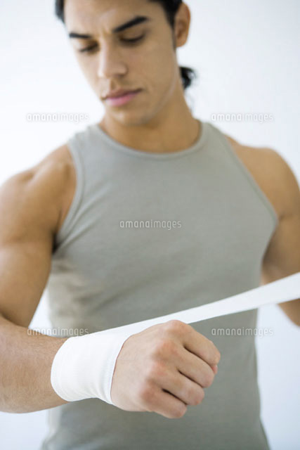 Man wrapping bandage around his wrist,looking down
(c)Alix Minde/PhotoAlto