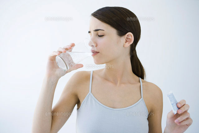 Woman drinking effervescent water,holding medicine packet
(c)Alix Minde/PhotoAlto