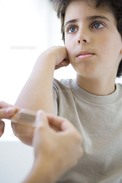 Boy having adhesive bandage applied to his elbow
(c)Alix Minde/PhotoAlto