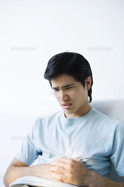 Young man holding his stomach and furrowing his brow
(c)Alix Minde/PhotoAlto