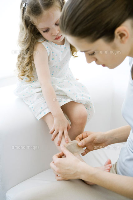 Mother putting adhesive bandage on young daughter’s leg
(c)Alix Minde/PhotoAlto