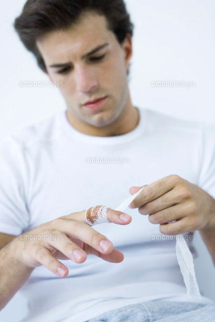 Man wrapping gauze around injured finger
(c)Alix Minde/PhotoAlto