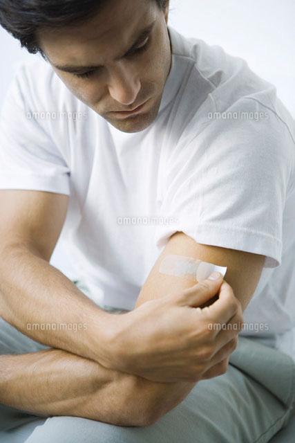Man putting adhesive bandage on his arm
(c)Alix Minde/PhotoAlto