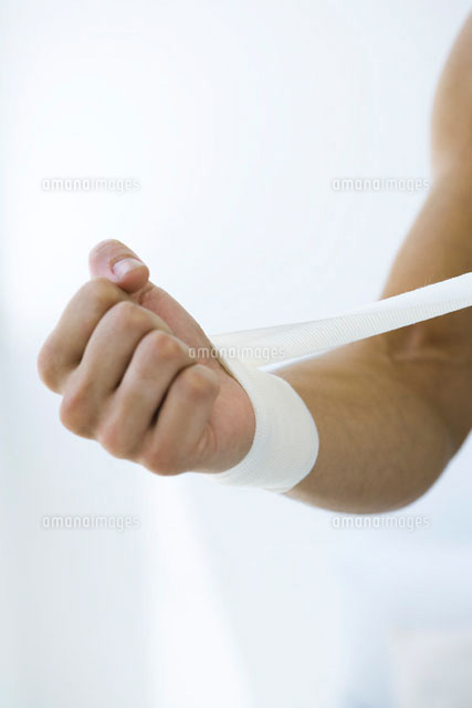 Man wrapping gauze around his wrist,cropped view
(c)Alix Minde/PhotoAlto