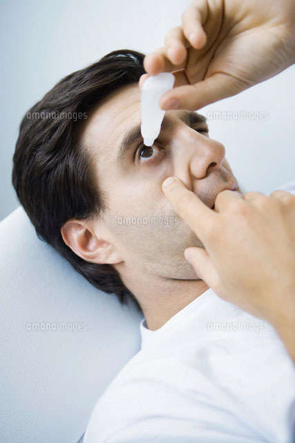 Man reclining,putting eyedrops in one eye
(c)Alix Minde/PhotoAlto