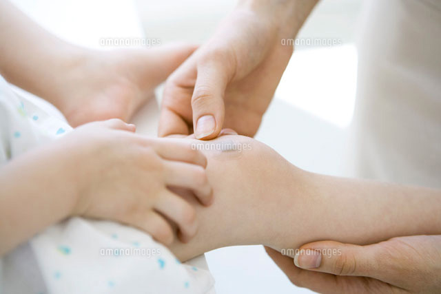 Adult placing adhesive bandage on child’s knee
(c)Alix Minde/PhotoAlto
