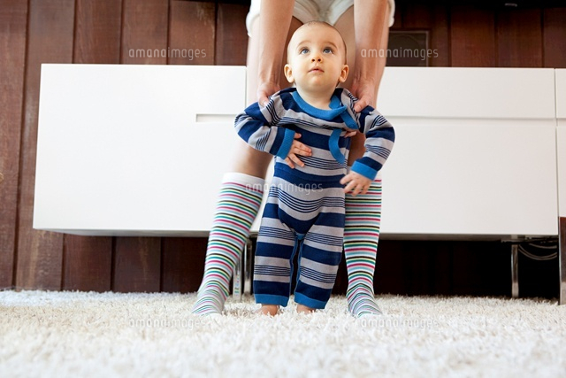 Mother helping baby son take first steps
(c)Image Source