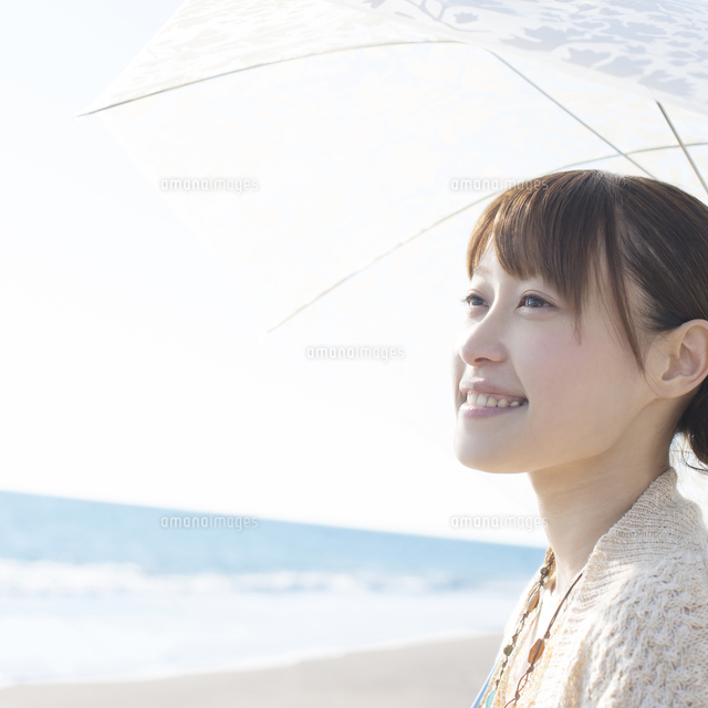 海で日傘をさし微笑む女性
(c)visual supple