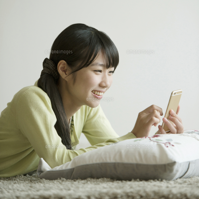 床に寝転びスマートフォンを見る女性
(c)visual supple