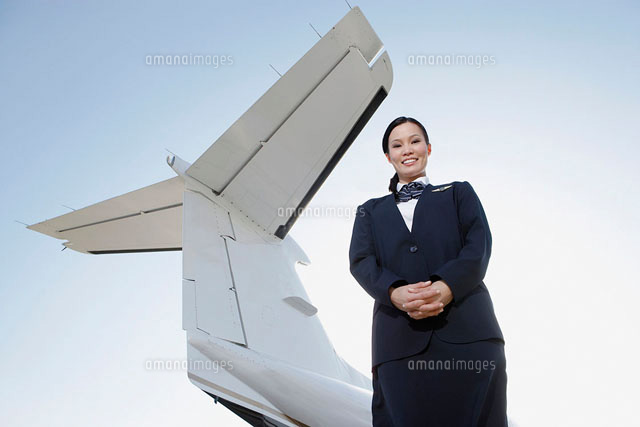 Stewardess in uniform standing below wing of private jet
(c)moodboard