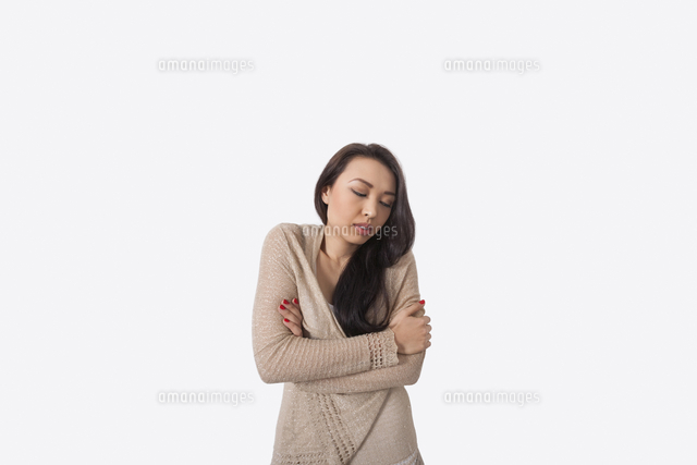 Young woman with arms crossed shivering against gray background
(c)moodboard