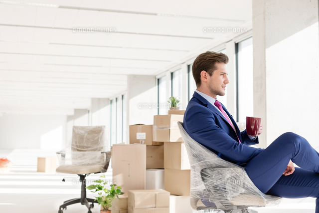 Side view of young businessman having coffee on chair in new office
(c)moodboard