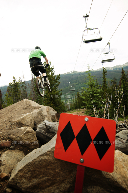 mountain biker riding down on rocks in forest 11100010563 写真