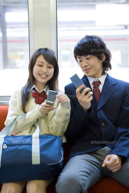 電車内で携帯電話を見ながら話す高校生
(c)DAJ