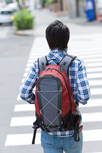 リュックを背負い横断歩道を渡る男性
(c)DAJ